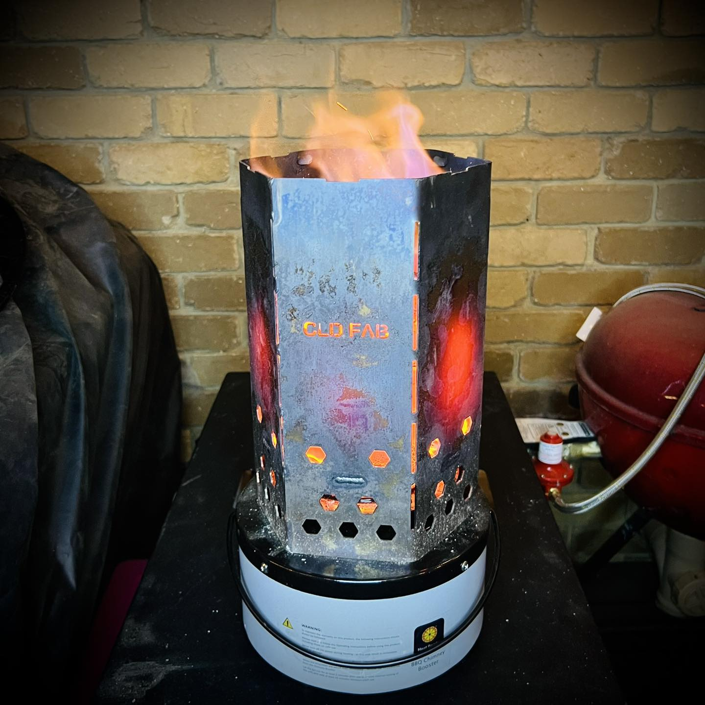 CLD Fabrication stainless steel chimney starter resting on a Heat Beads Booster for Weber Kettle