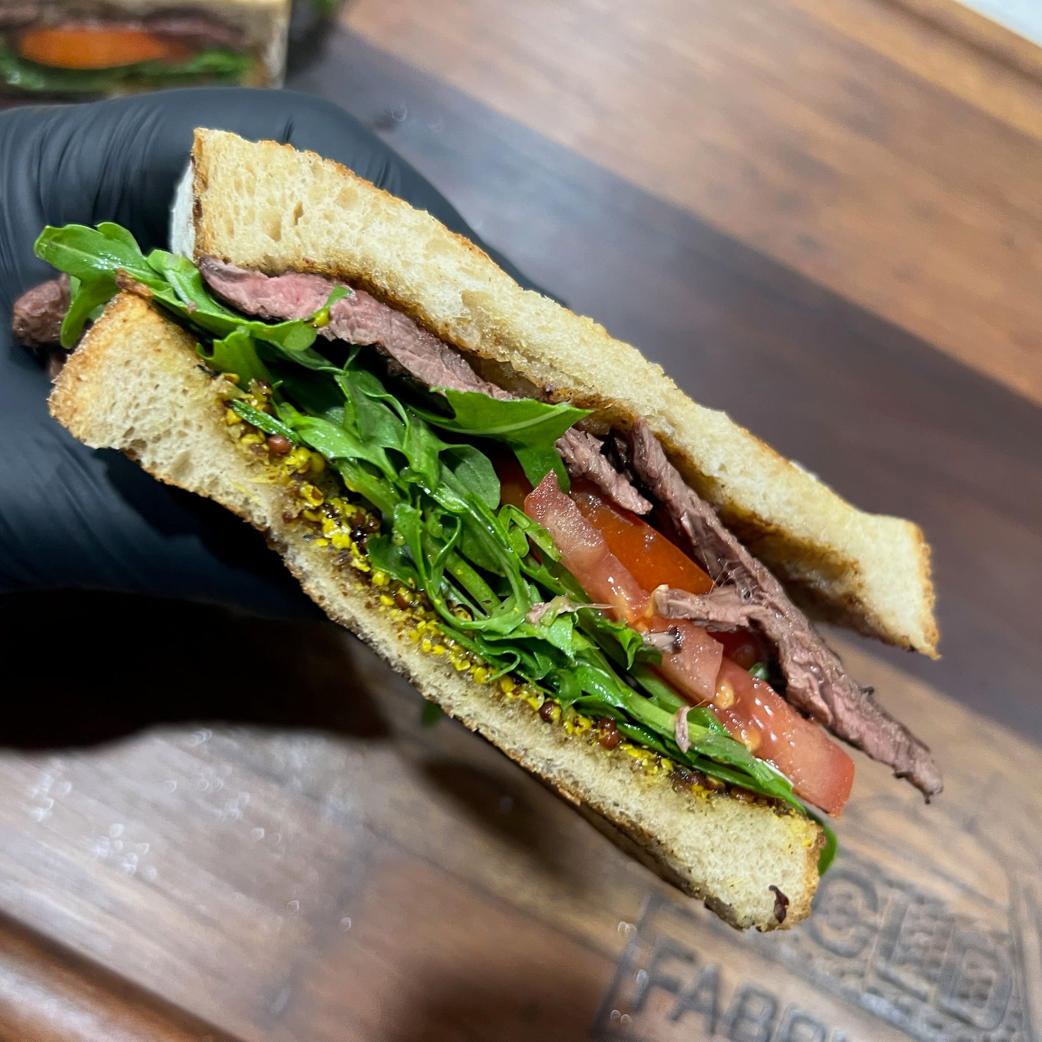 High protein kangaroo sandwich cut in half on a hardwood chopping board with bocconcini and rocket