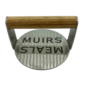 Stainless burger smasher with Muir Meals logo and wooden handle
