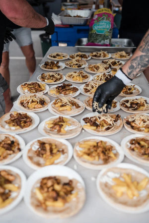 Rows of smoked BBQ meat plates being finished and garnished at a Firehouse Barbecue class