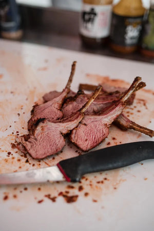 Freshly sliced smoked lamb cutlets on a chopping board at Smoke School BBQ class