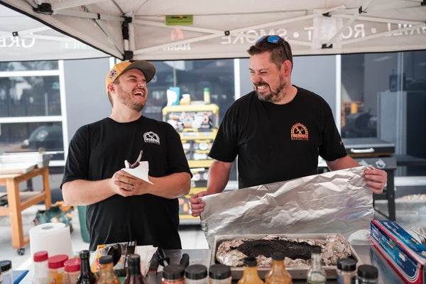 Two Firehouse Barbecue pitmasters unwrapping foil-rested smoked meat during a BBQ class