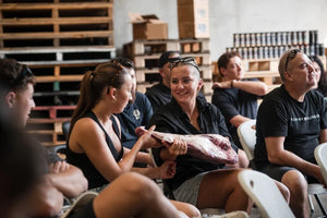 BBQ class participants handling a raw lamb shoulder during a hands-on Smoke School session